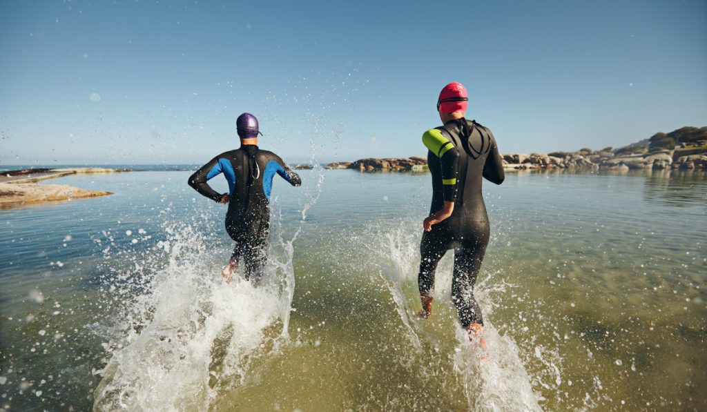 two athletes running to swim for a triathlon