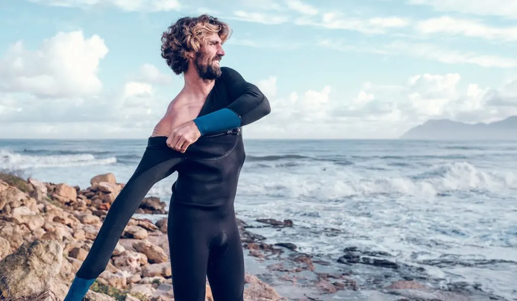 young lad putting on a surf wet suit