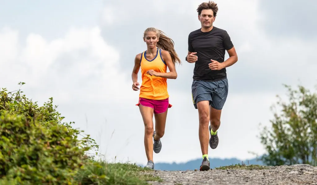 Couple of trail runners running together in an open field 