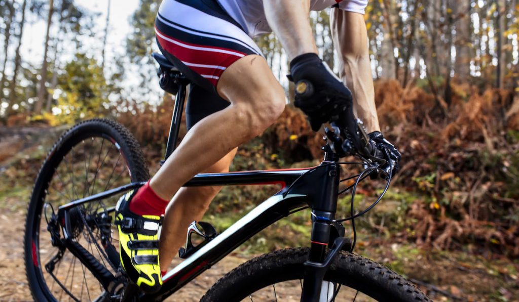 Mountain biker driving in the forest, close-up wearing cycling short 