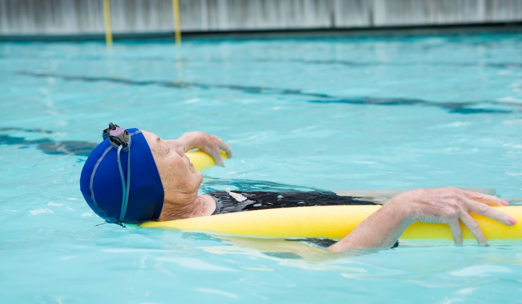 Senior woman swimming in pool wearing swimming cap