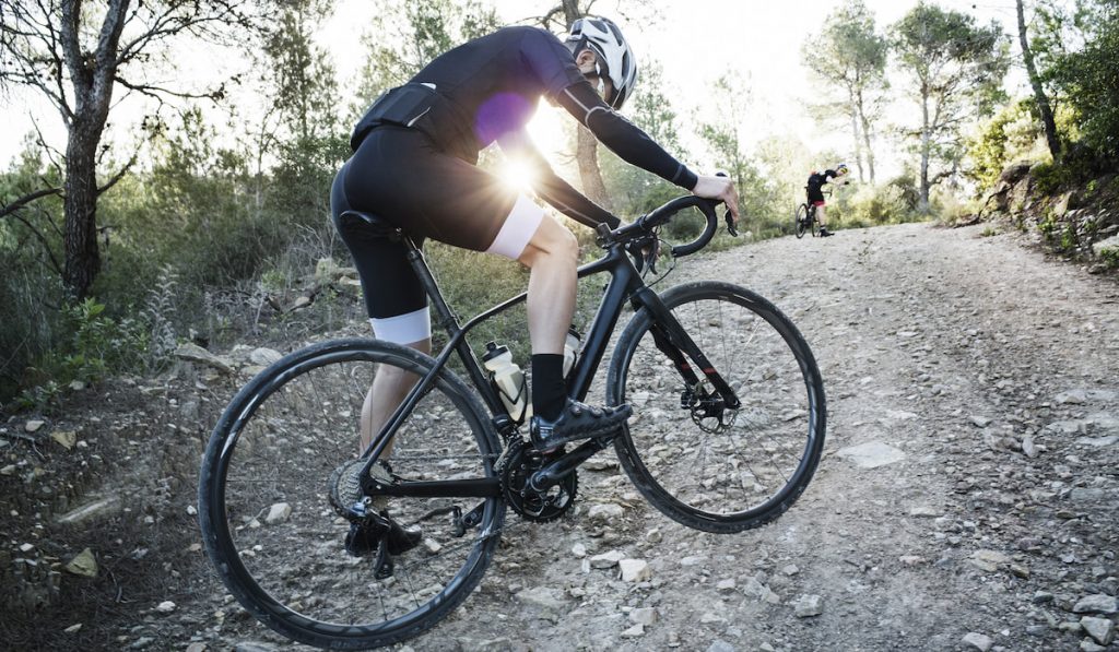 Side View Of Man Cycling On Dirt Road wearing leg grippers 