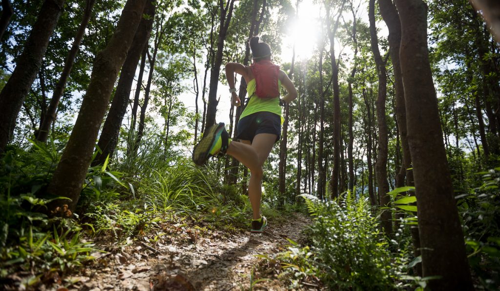 Young woman trail runner running in tropical forest