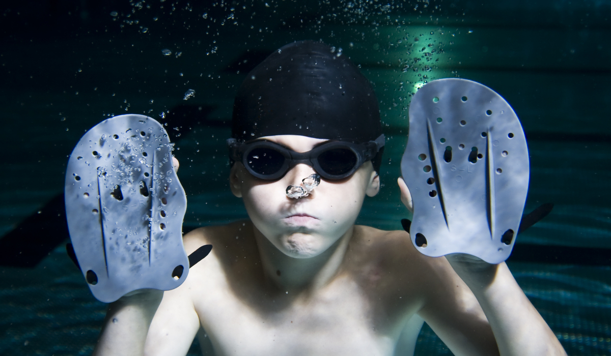 Little-boy-underwater-the-pool-with-swimming-hand-paddles