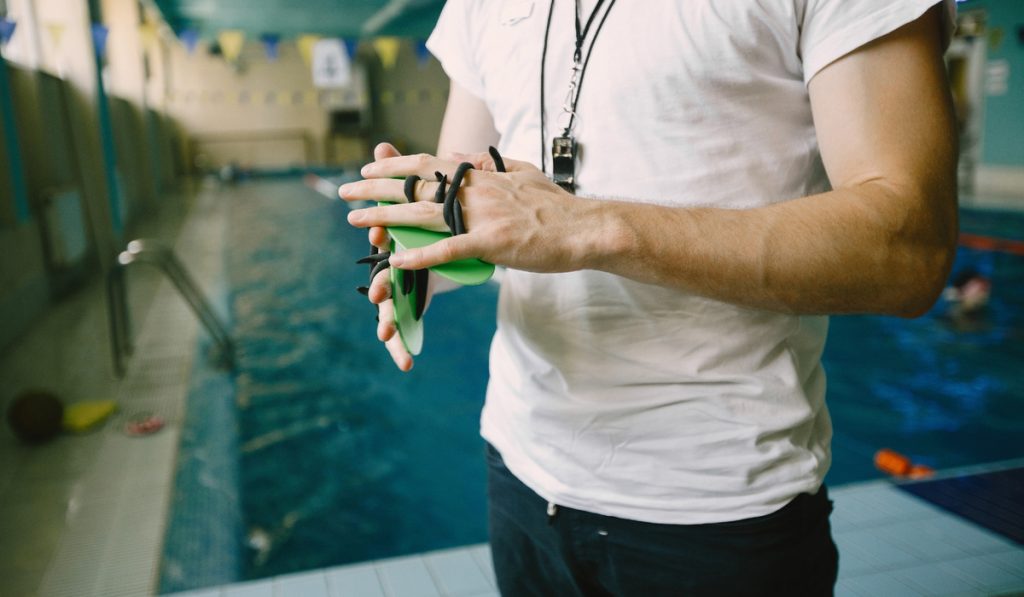 Swimming trainer showing how to use hand paddle