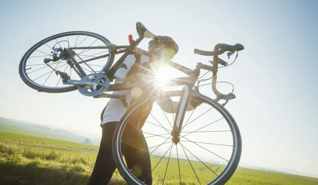 A man carrying a road bike on his shoulder.
