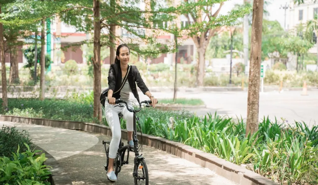 Happy woman riding her folding bike in the park