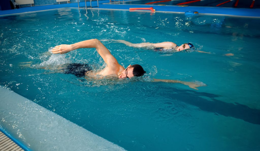 Male and female swimmers swims in the pool
