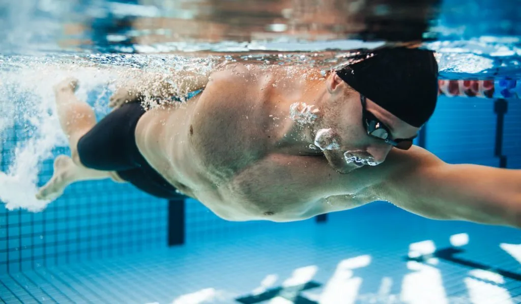 Professional male swimmer swimming in pool
