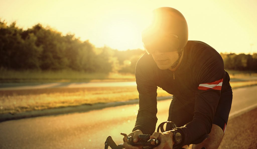 The cyclist riding bike during sunset