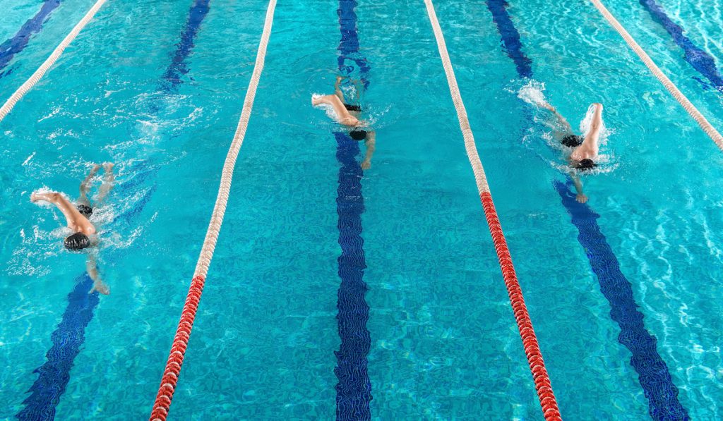 Three male swimmers racing against each other
