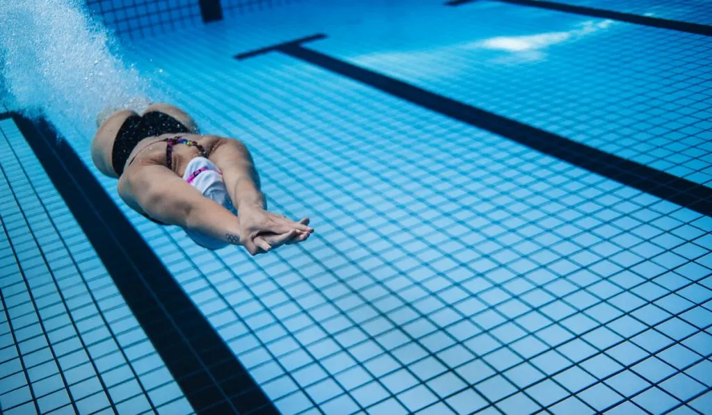 Woman training in swimming pool gliding freestyle