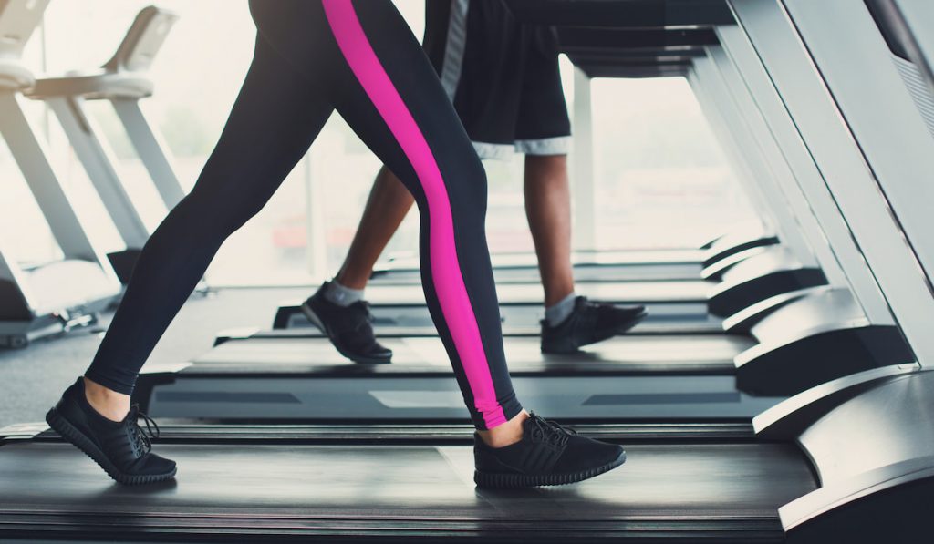 Woman's legs on treadmill in fitness club
