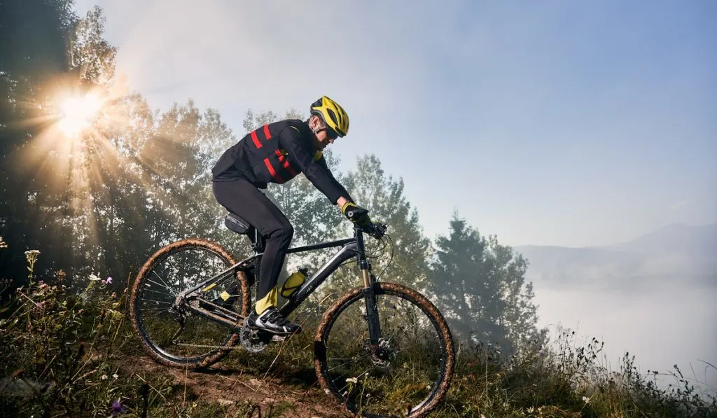 Young man riding bicycle in the mountains in early morning
