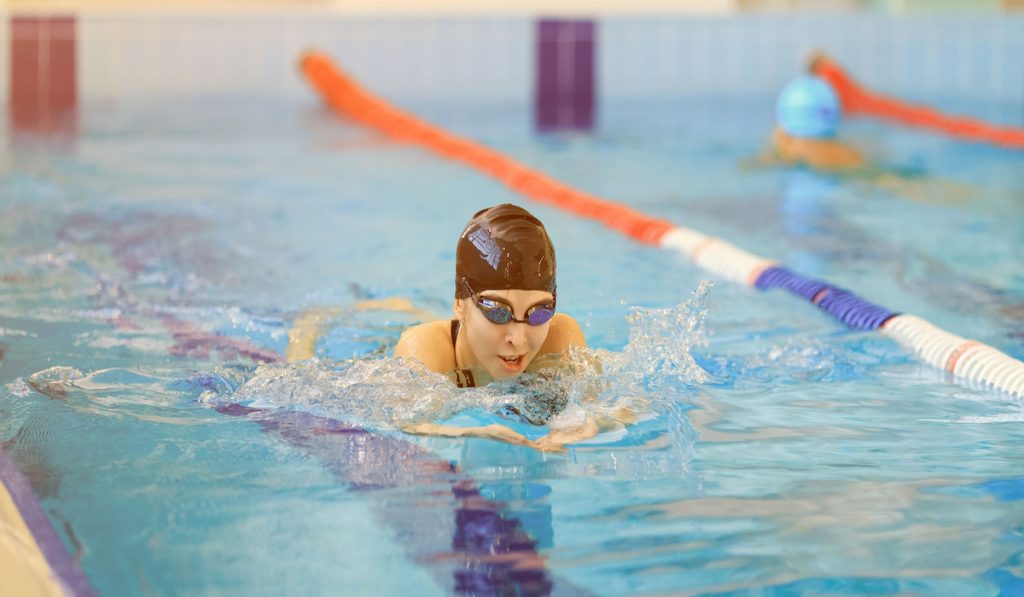 Young woman with googles doing breaststroke in the pool 