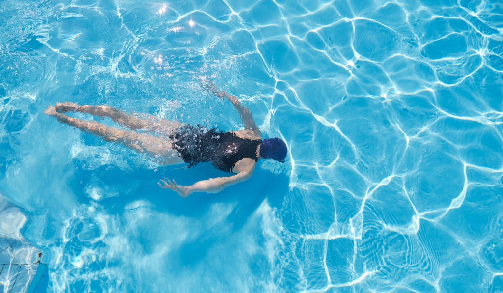 woman swimming underwater in an outdoor pool